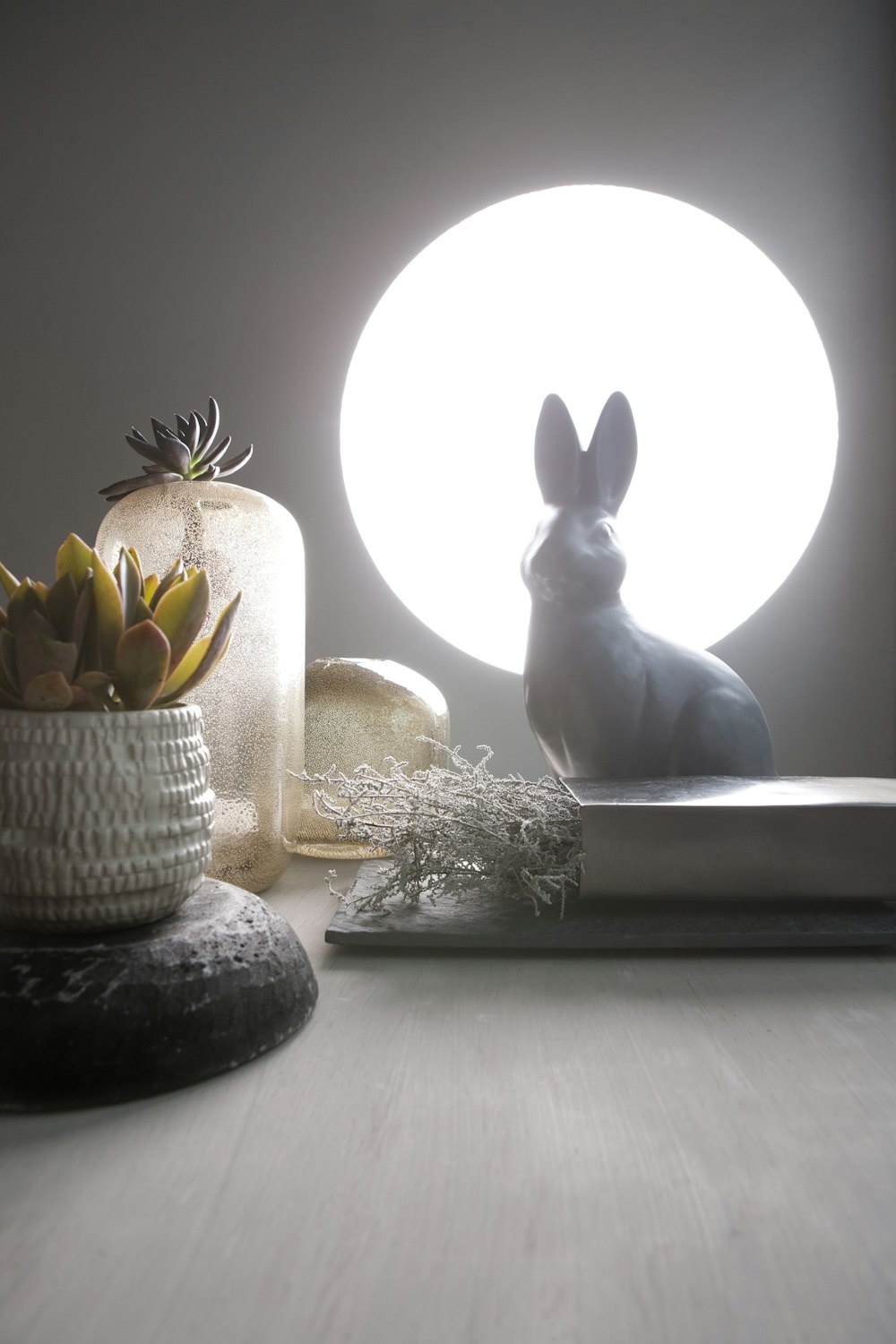 a small rabbit sitting on a table next to a potted plant