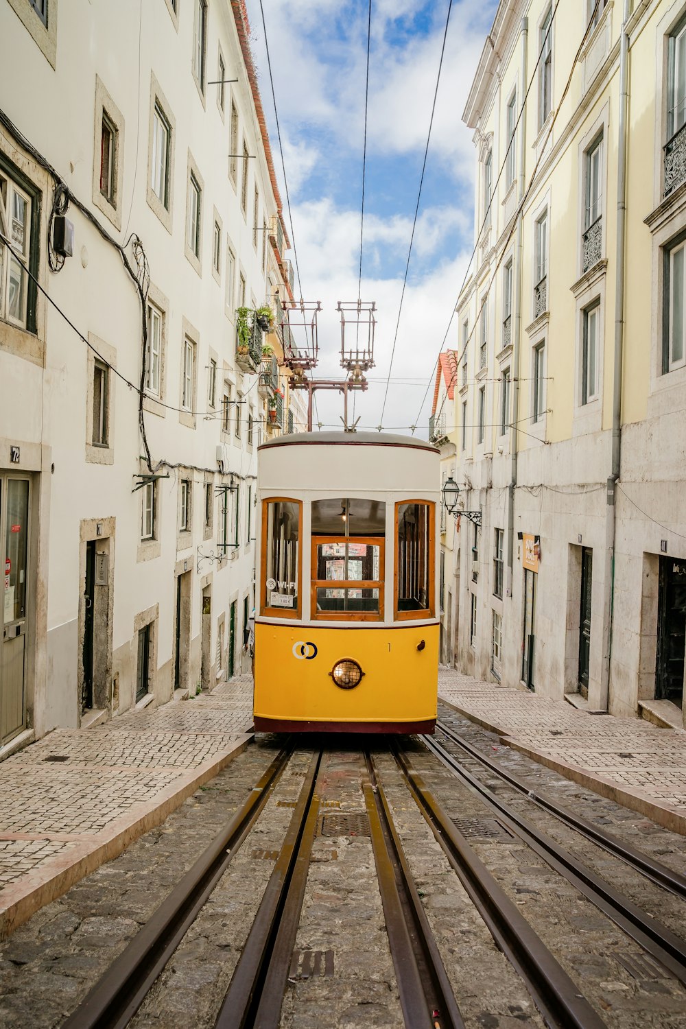 a yellow trolley car traveling down a street next to tall buildings