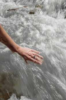 a hand reaching for something in the water