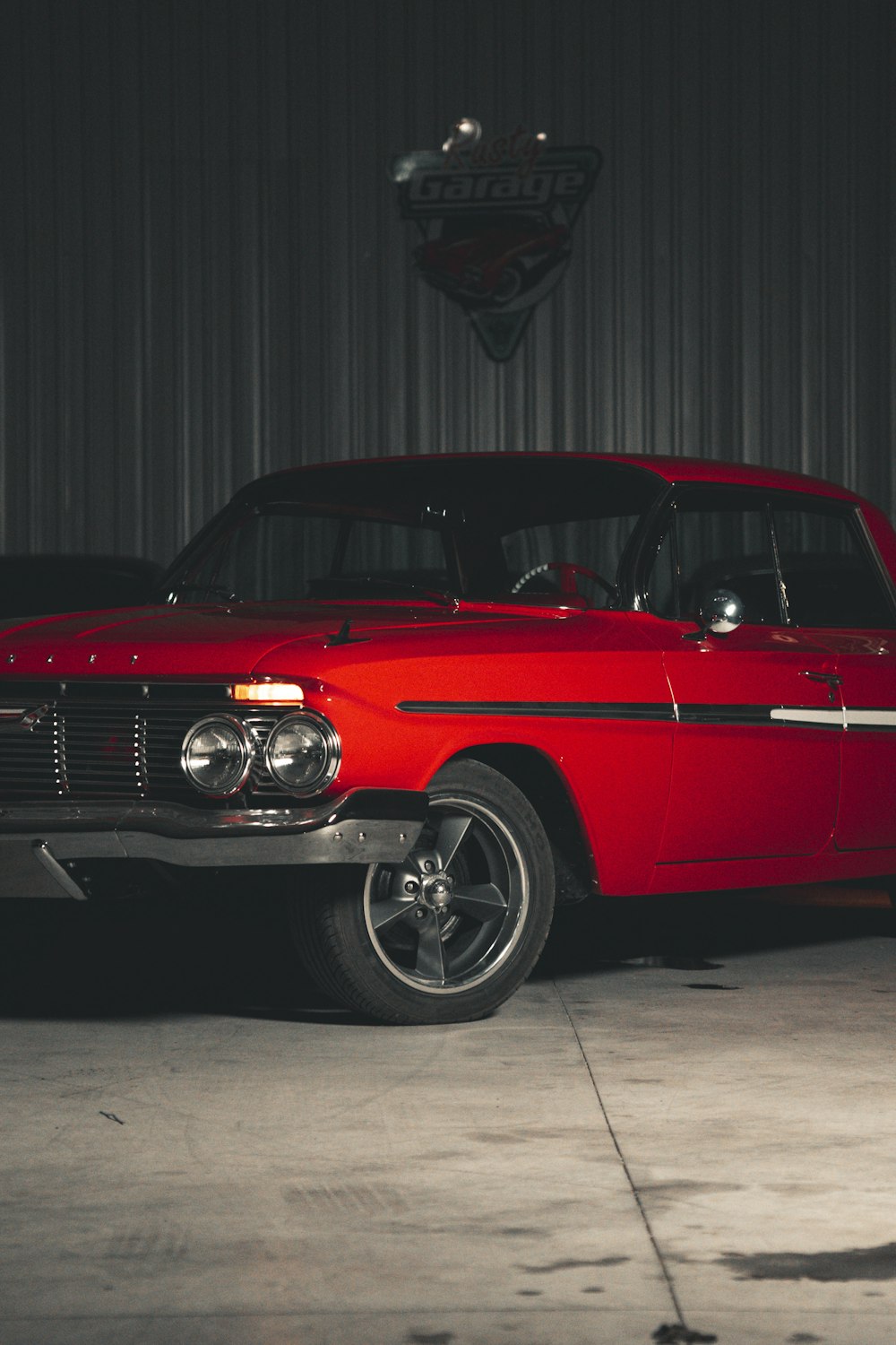 a red classic car parked in a garage