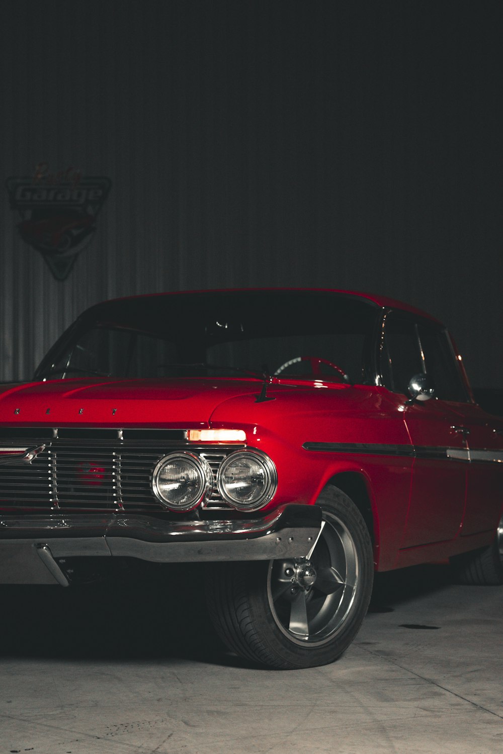 a red classic car parked in a garage