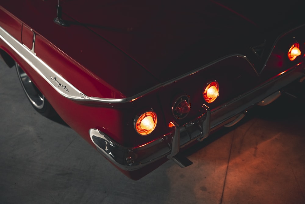 a close up of a red car with its lights on
