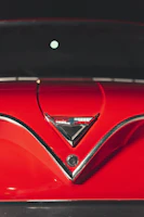 Close-up of a shiny restored classic car hood with gleaming chrome details.