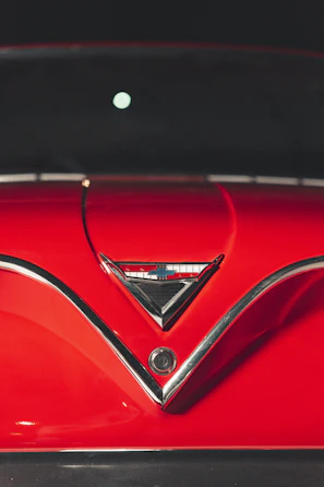 Close-up of a shiny restored classic car hood with gleaming chrome details.