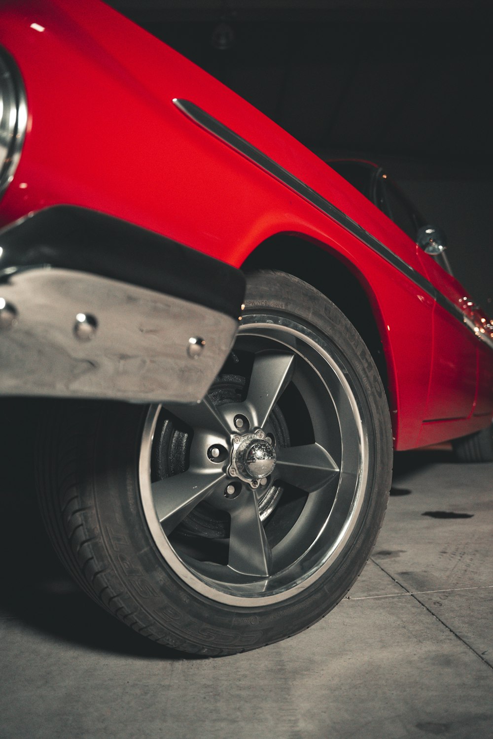 a red car parked in a garage next to another car