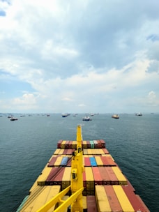 A cargo ship loaded with containers navigating through a busy port.