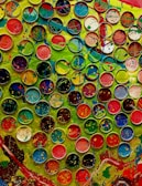 Hands painting a vibrant abstract design, surrounded by scattered paint tubes.