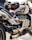 A close-up view of a powerful motorcycle featuring a sleek design with metallic and black components. The engine and exhaust system are prominently displayed, and a small bag is attached on top. The motorcycle tank displays a Union Jack design.
