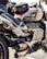 A close-up view of a powerful motorcycle featuring a sleek design with metallic and black components. The engine and exhaust system are prominently displayed, and a small bag is attached on top. The motorcycle tank displays a Union Jack design.