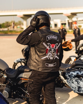 a man in a leather jacket standing next to a motorcycle