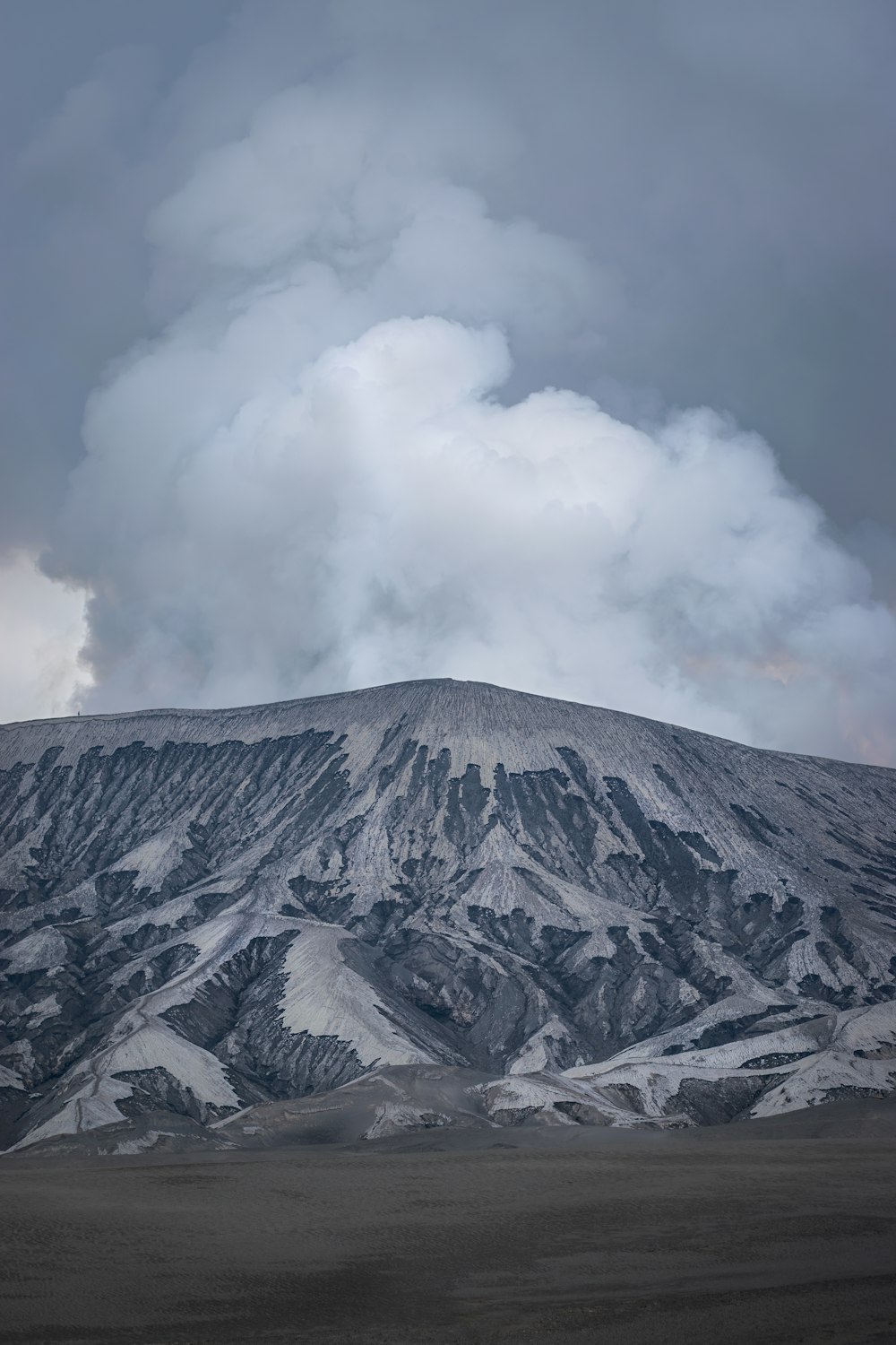 a large mountain covered in snow under a cloudy sky