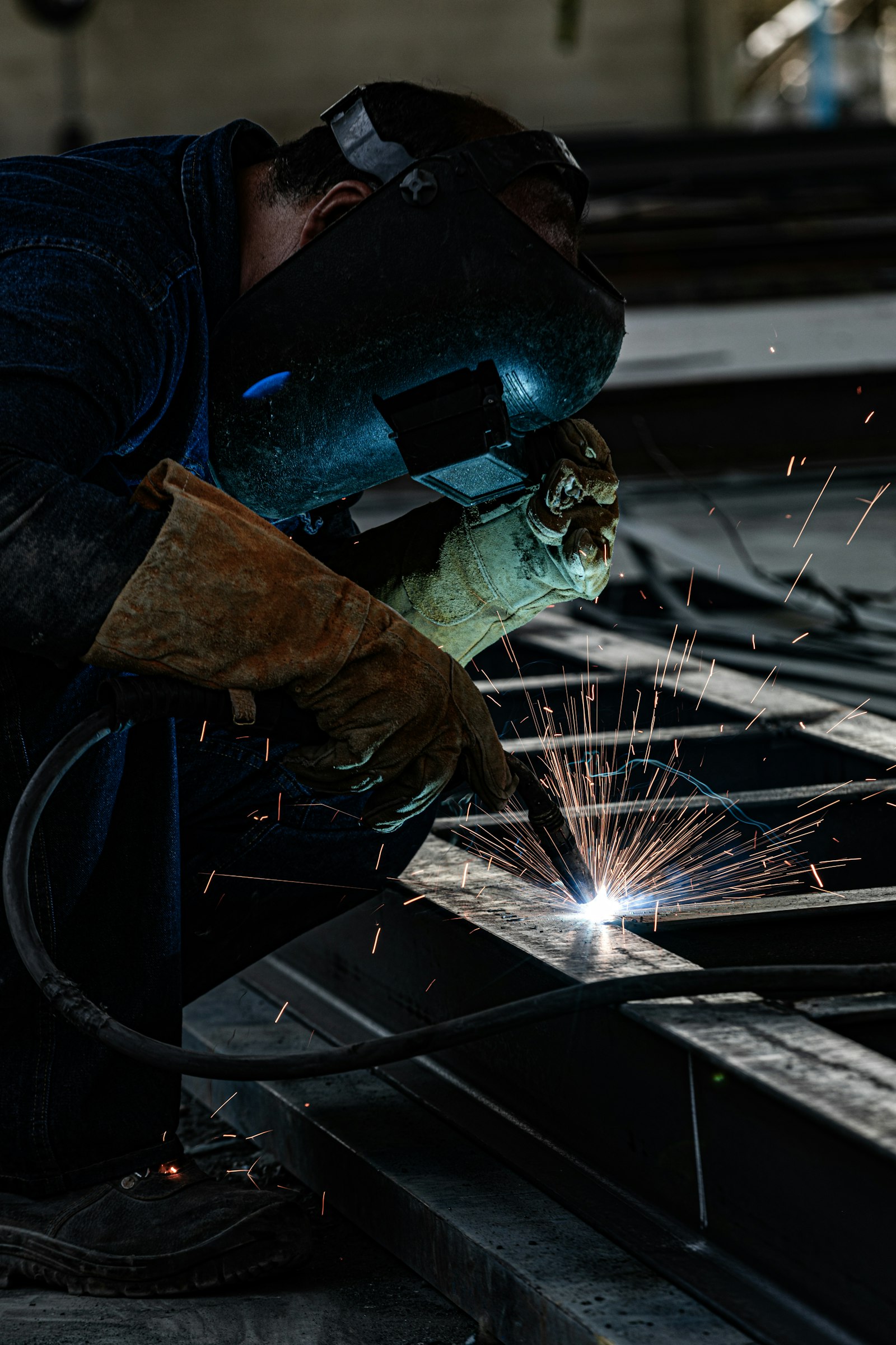 Fabricator grinding a structural steel beam, sparks flying