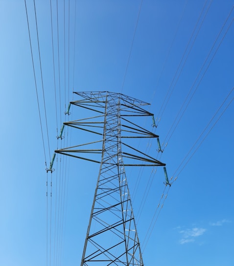 A sleek high-voltage transmission tower standing tall against a clear blue sky, symbolizing strength and reliability.