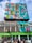 A vibrant mural covers the upper section of a multi-story building. The artwork features geometric patterns and a variety of bright colors including teal, pink, yellow, and orange. Below, a green sign indicates a job center. People are visible at ground level, walking past the building. A person is elevated on a cherry picker, possibly engaged in work on the mural.