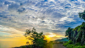 A scenic coastal view of Australia with a winding road and vibrant sunset.