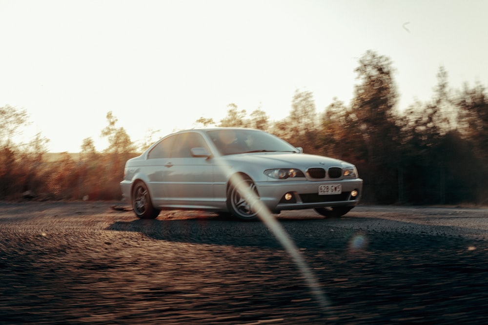 a white car driving down a dirt road