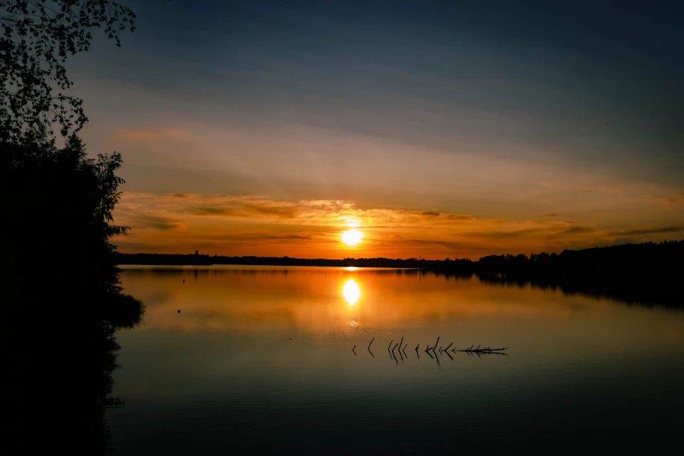 Serene sunset over calm lake with warm glow and vibrant sky reflections