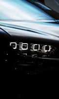 A close-up view of a car's sleek, modern headlight with a reflective surface and a glossy finish, displaying intricate LED light design.
