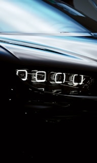 A close-up view of a car's sleek, modern headlight with a reflective surface and a glossy finish, displaying intricate LED light design.