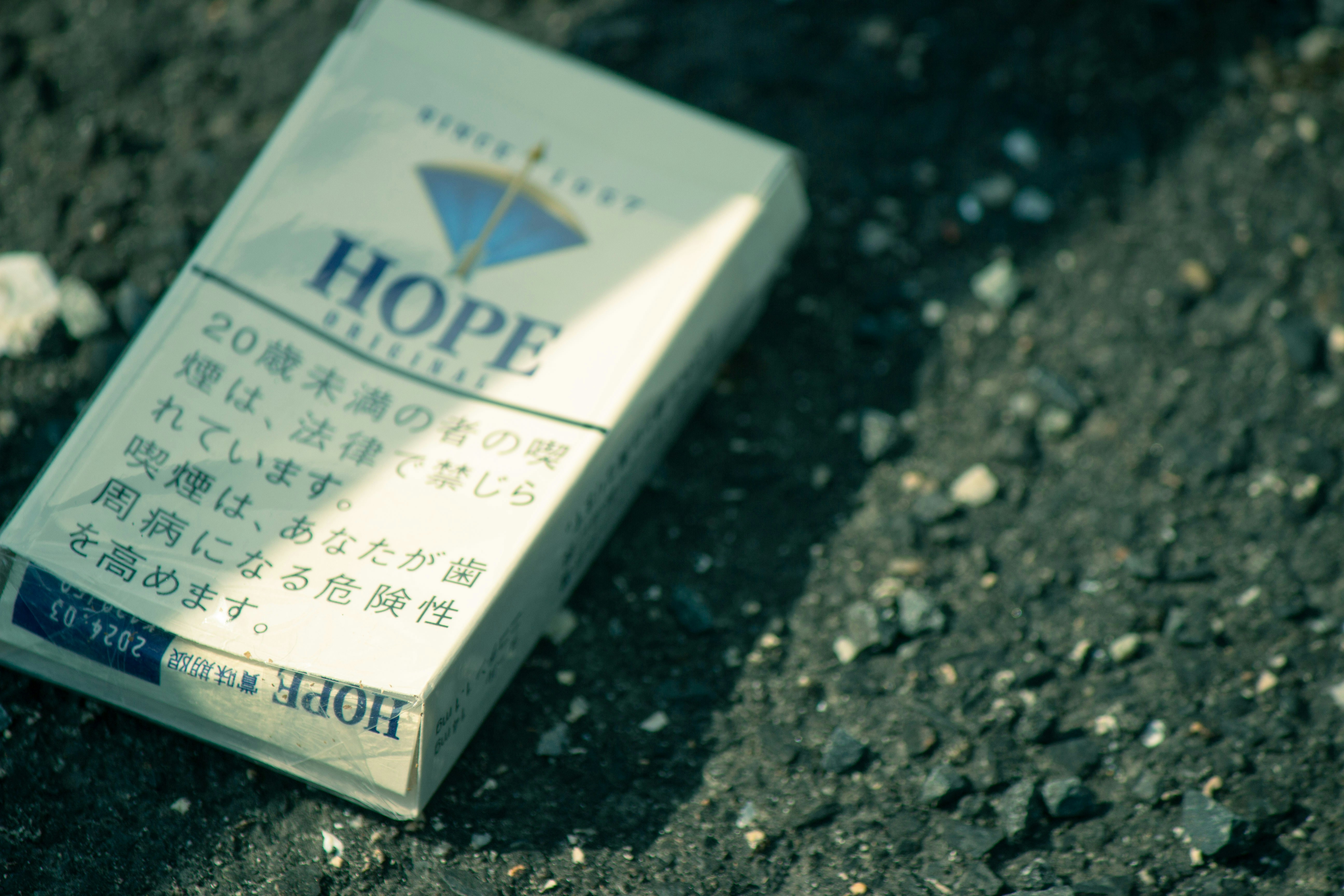 A cigarette box sitting on the ground with writing on it - Unsplashに収録の無料写真