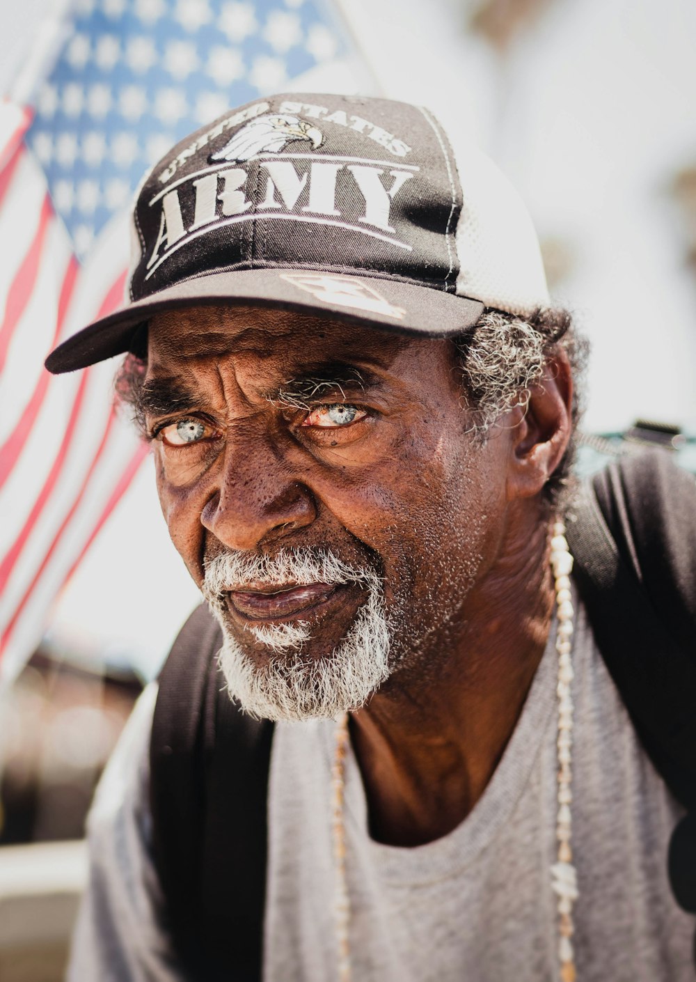 an old man with a hat and american flag in the background