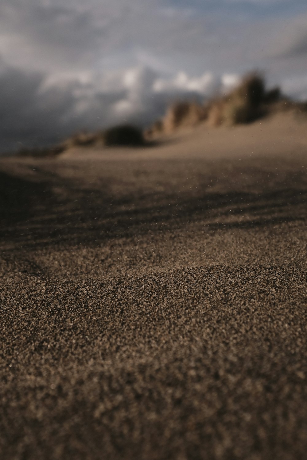 a blurry photo of a sand dune with clouds in the background