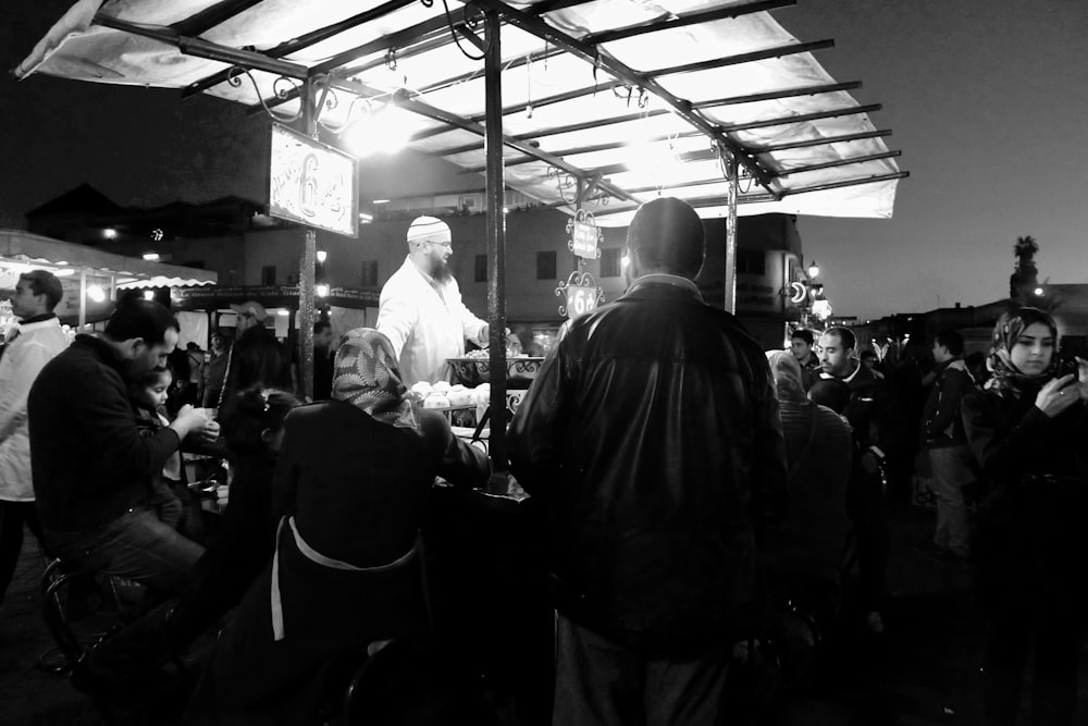 a group of people standing around a bar at night