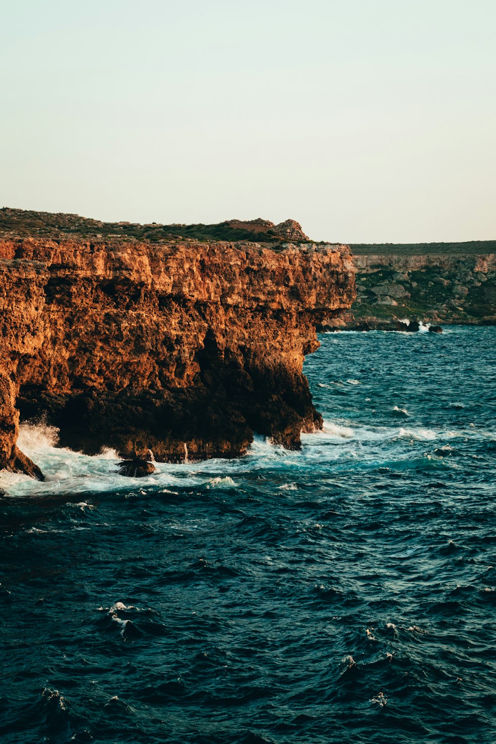 a large body of water next to a rocky cliff