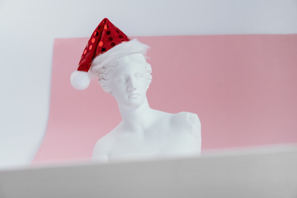 a white mannequin wearing a red santa hat