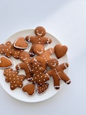 A plate filled with gingerbread cookies in various shapes, including gingerbread men, trees, and hearts, all decorated with white icing details.