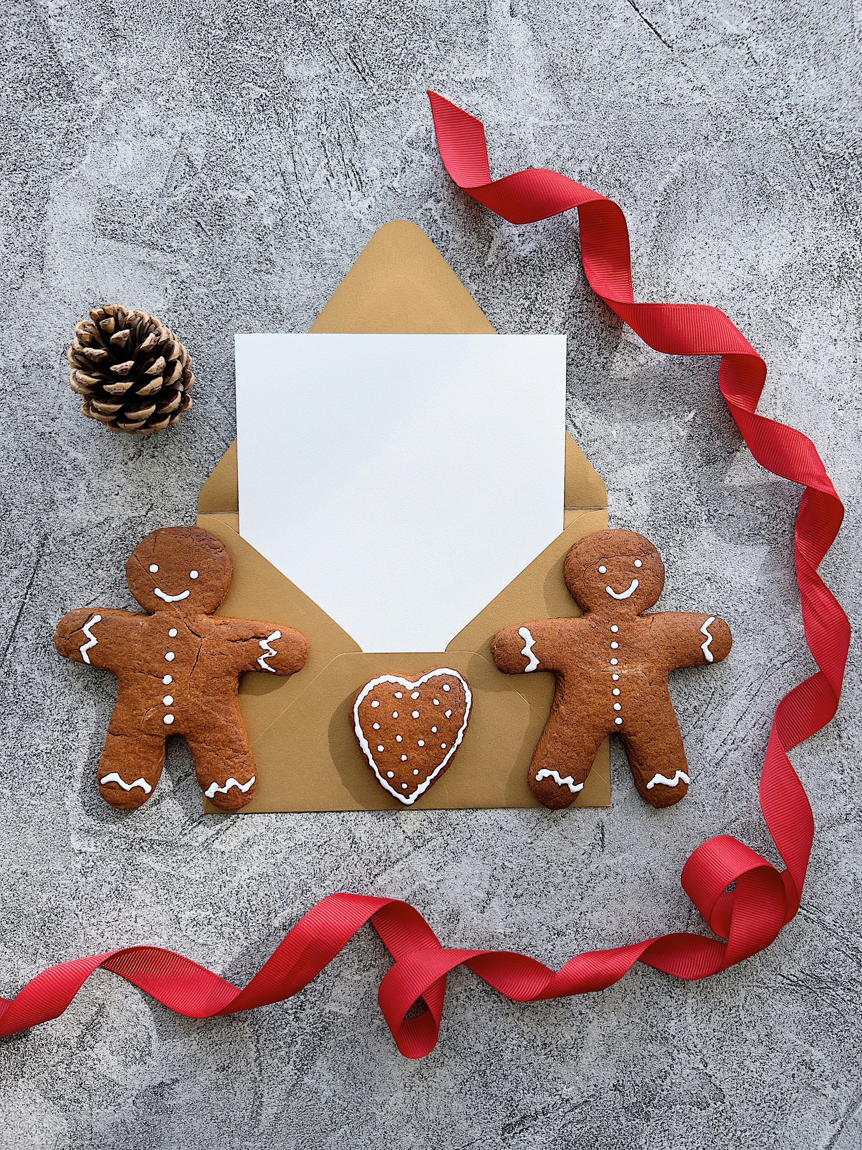 two gingerbread men holding a letter and a pine cone