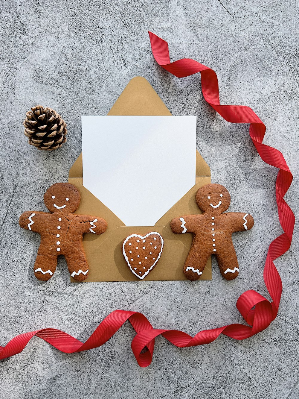 two gingerbread men holding a letter and a pine cone