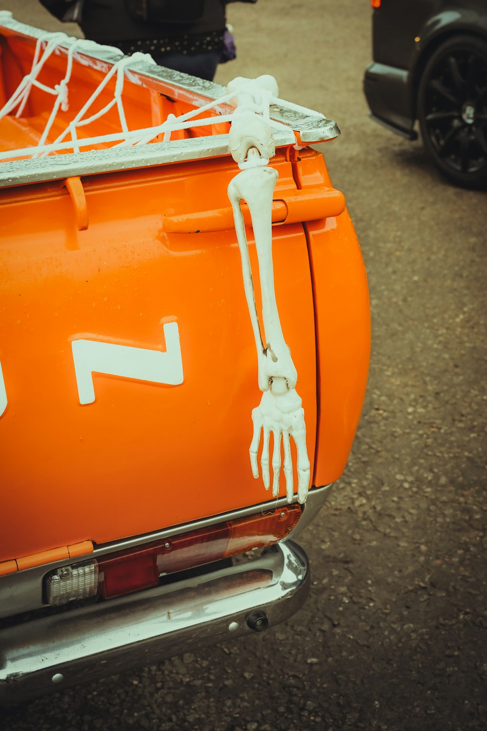 a skeleton sitting on the back of an orange vehicle