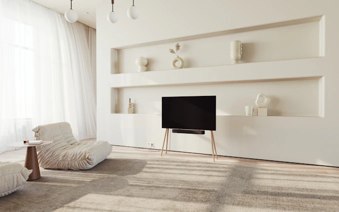 A serene minimalist living room with soft natural light and subtle video art on the walls.