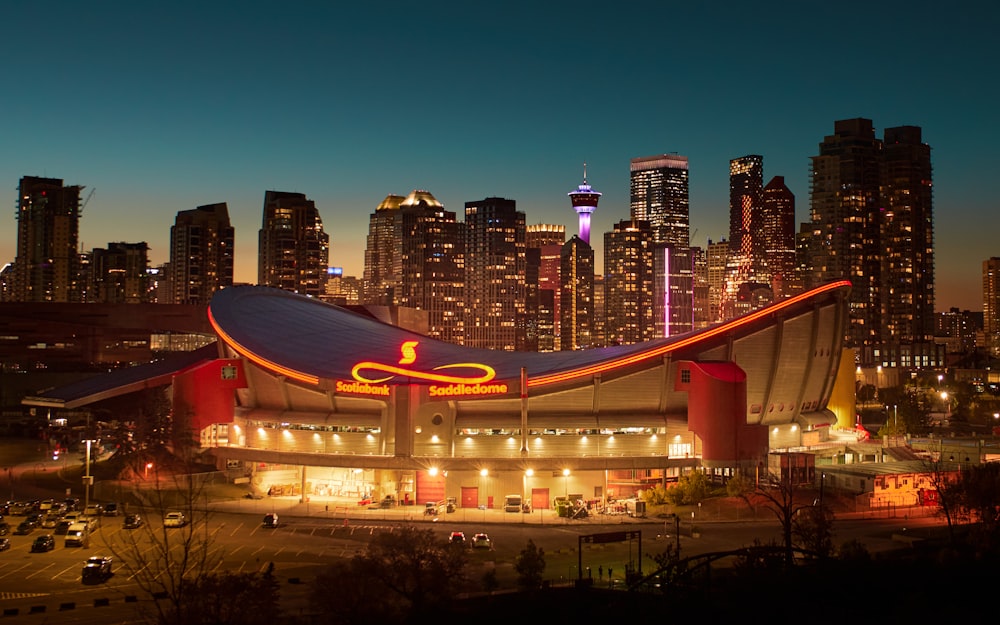 a large building with a lit up sign in front of a city skyline