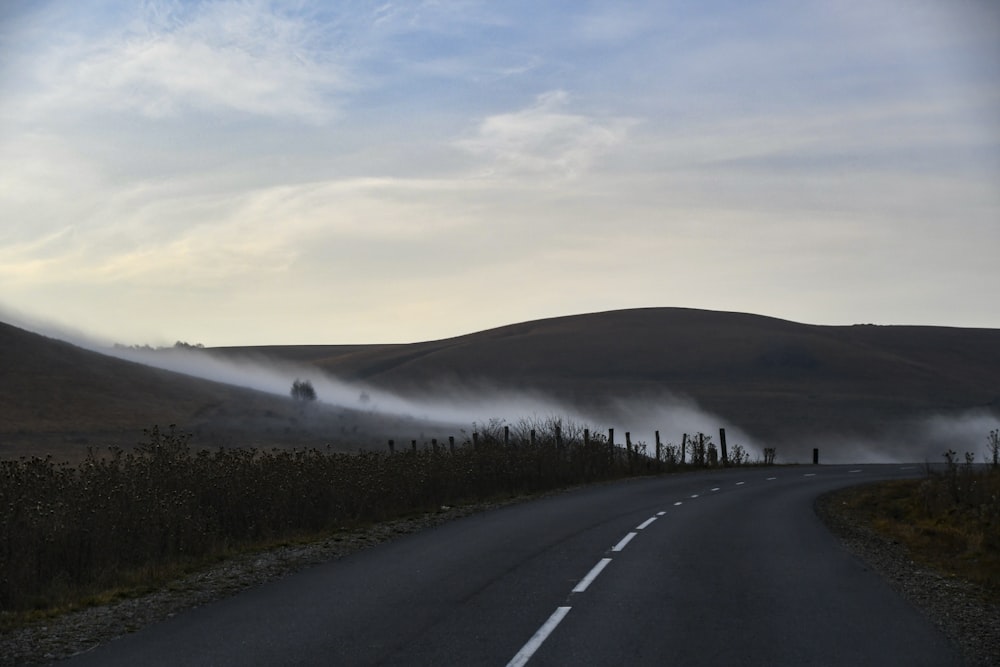 a foggy road with hills in the distance