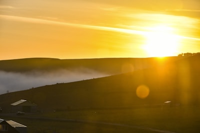 Sunrise casting golden light over a farmhouse roof and the rolling hills beyond.