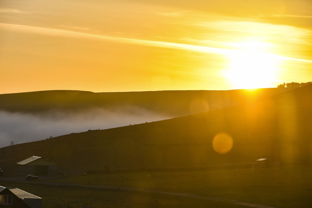 the sun is setting over a foggy valley