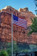 an american flag flying in front of a mountain