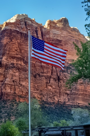 an american flag flying in front of a mountain