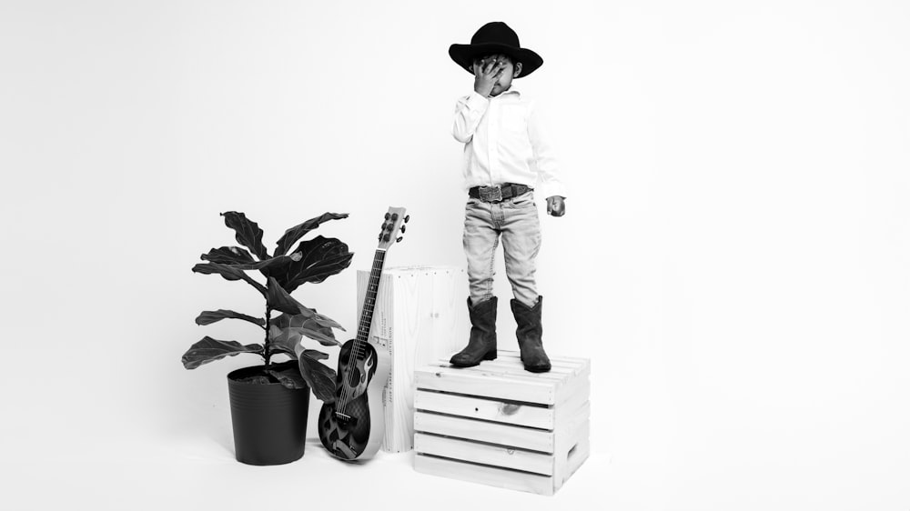 a black and white photo of a young boy wearing a cowboy hat