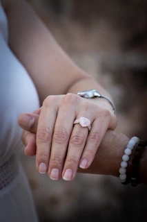 Close-up of intertwined hands wearing complementary rings and bracelets