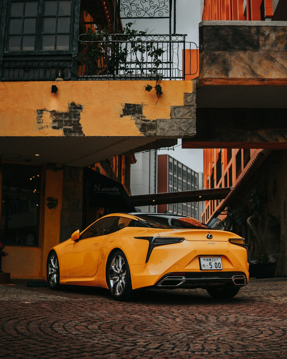 a yellow sports car parked in front of a building