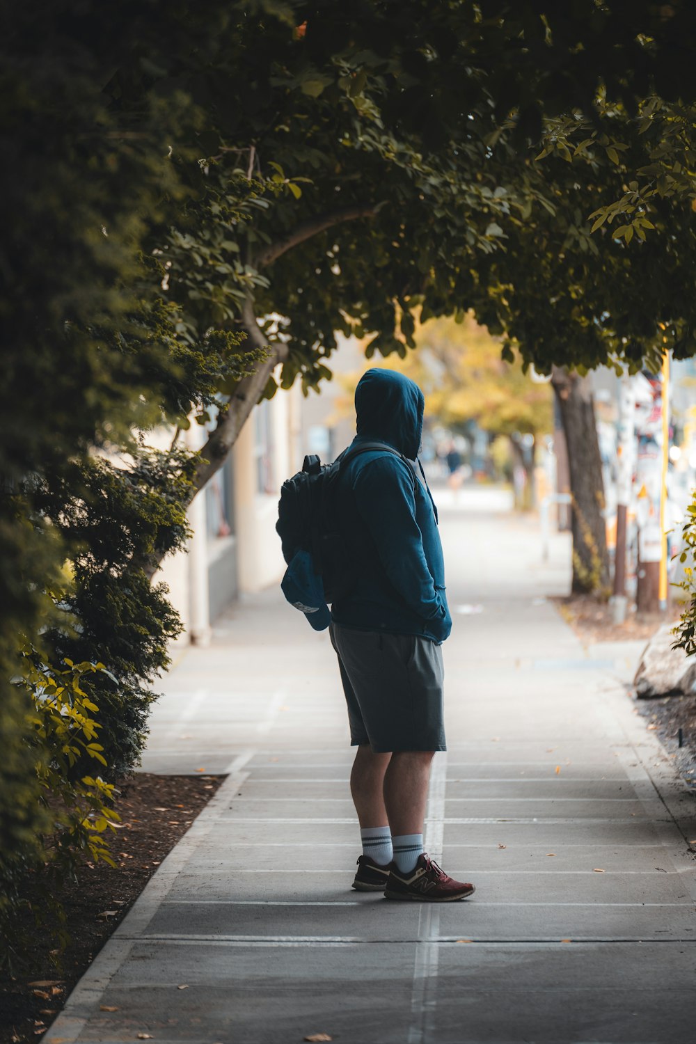 a person standing on a sidewalk with a backpack