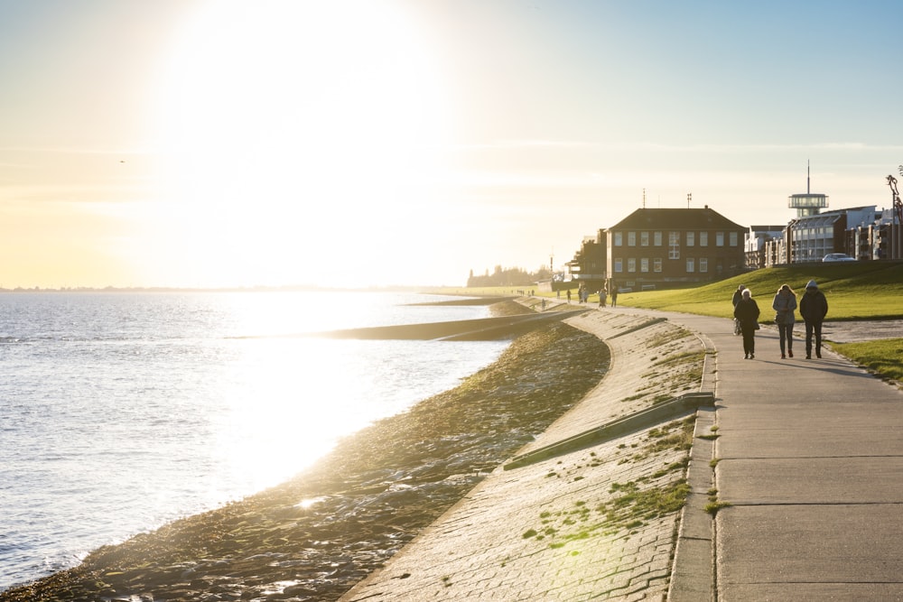 a group of people walking down a sidewalk next to the ocean