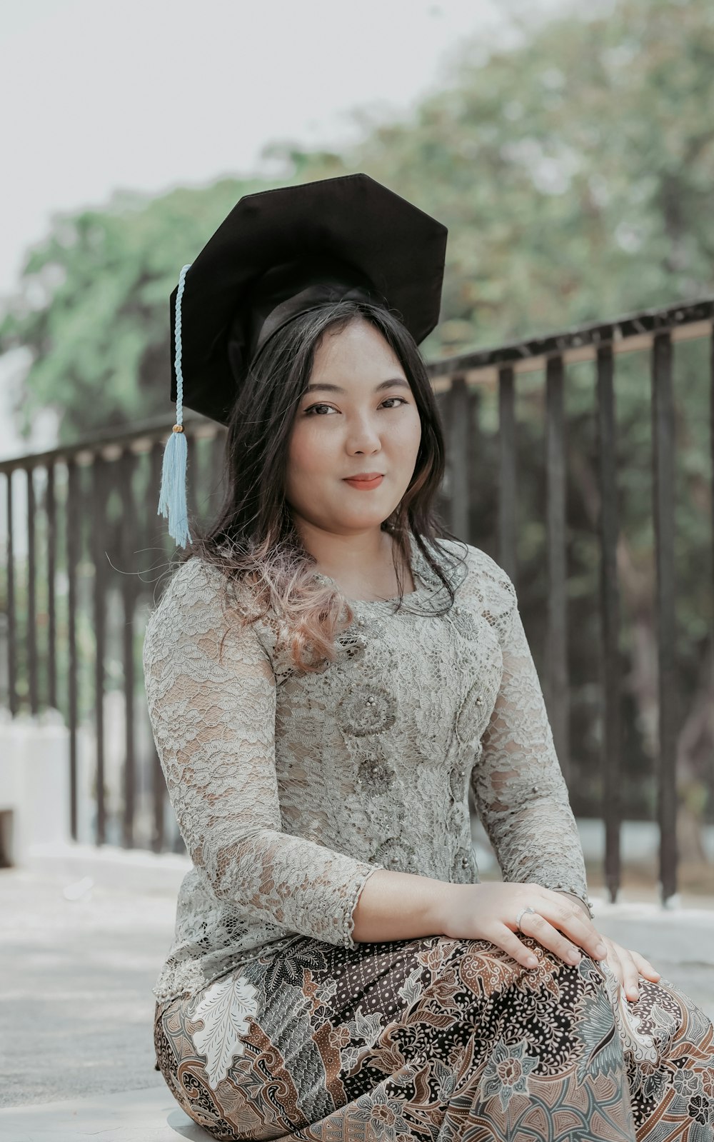 a woman sitting on the ground wearing a graduation hat