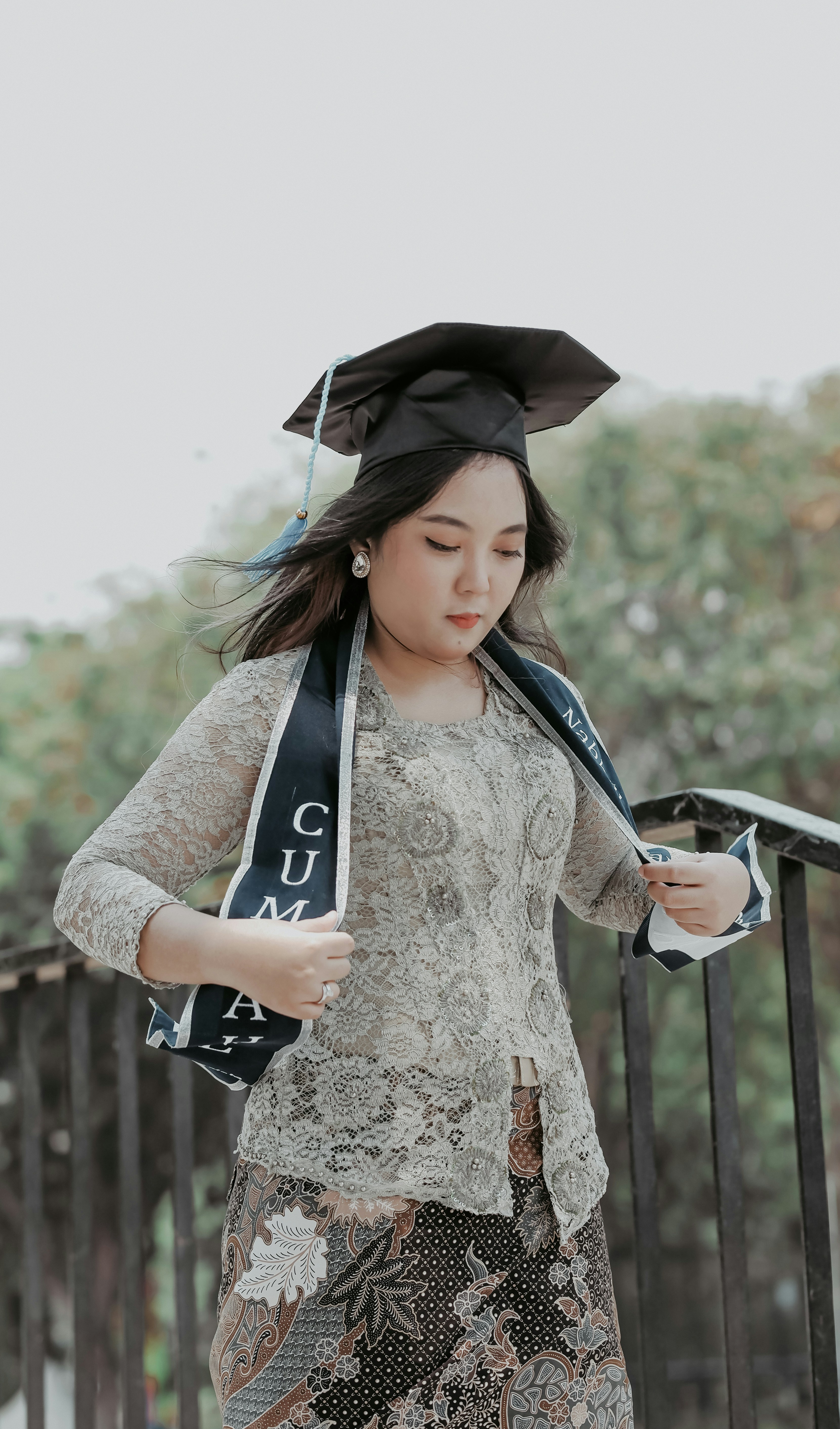 seorang wanita mengenakan topi dan gaun kelulusan