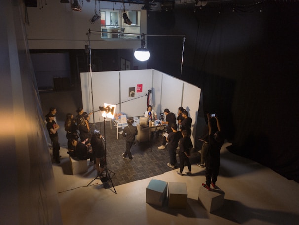 Behind-the-scenes shot of a video shoot with cameras and lighting equipment set up in a modern office space.