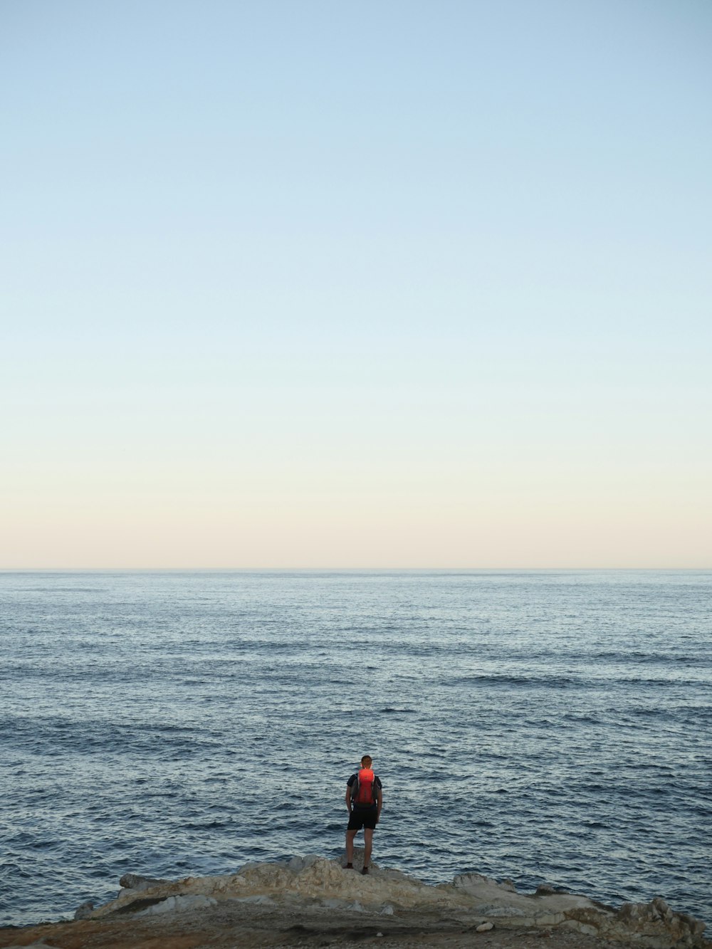 a man standing on top of a rock next to the ocean