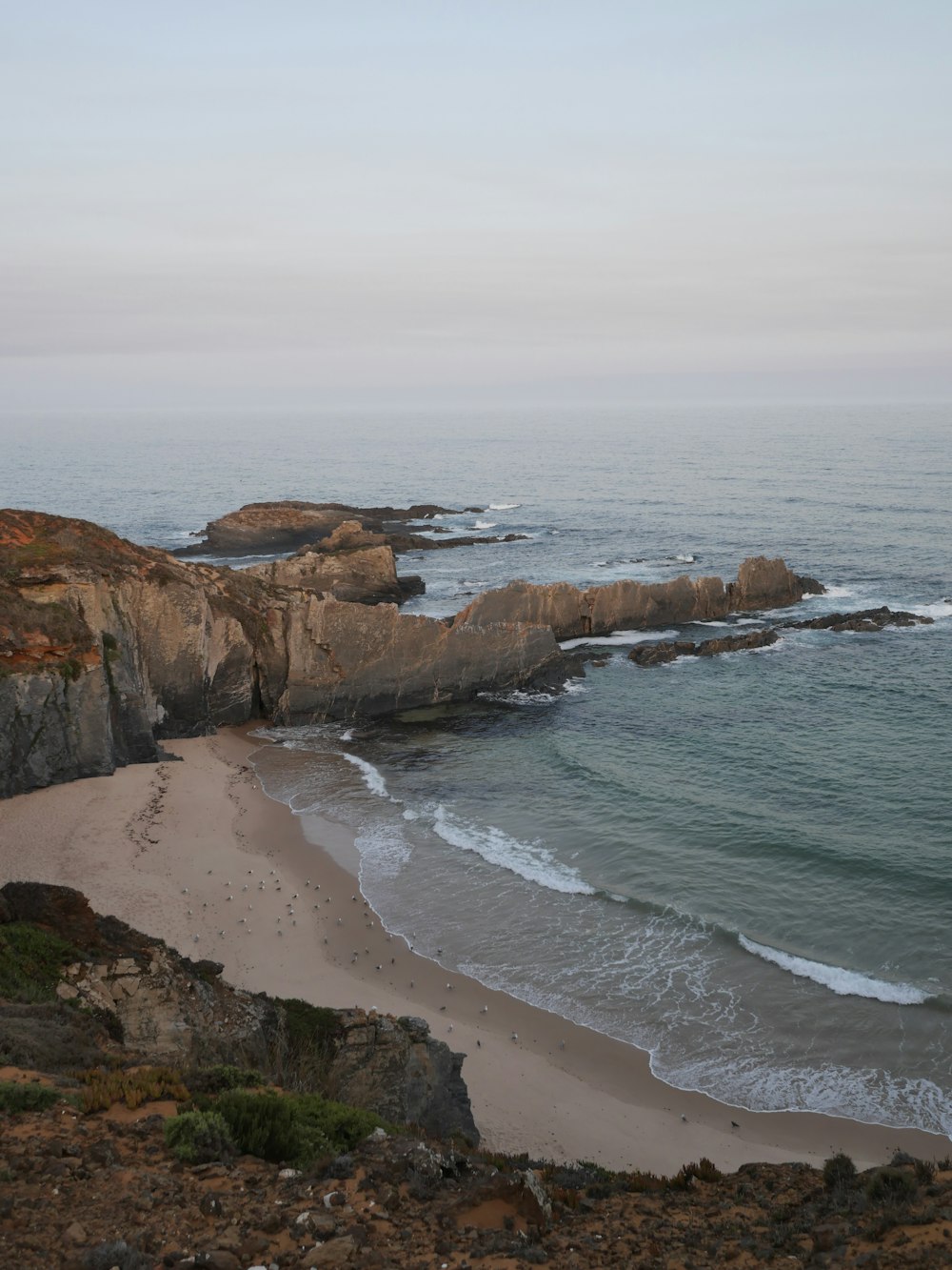 a sandy beach next to a rocky cliff